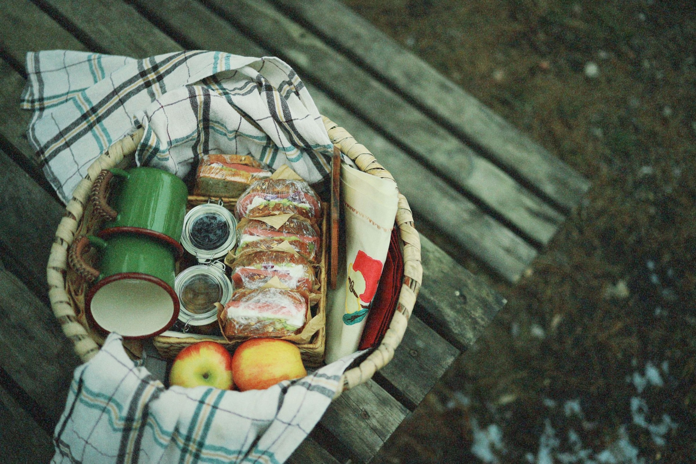 Nappe posée dans l'herbe avec pain, fromage, tomates cerises, fruits et bouteilles d'eau pour un pique-nique improvisé